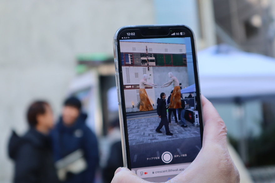 写真:マートフォンで映した、現実空間にアーティストが出現している映像