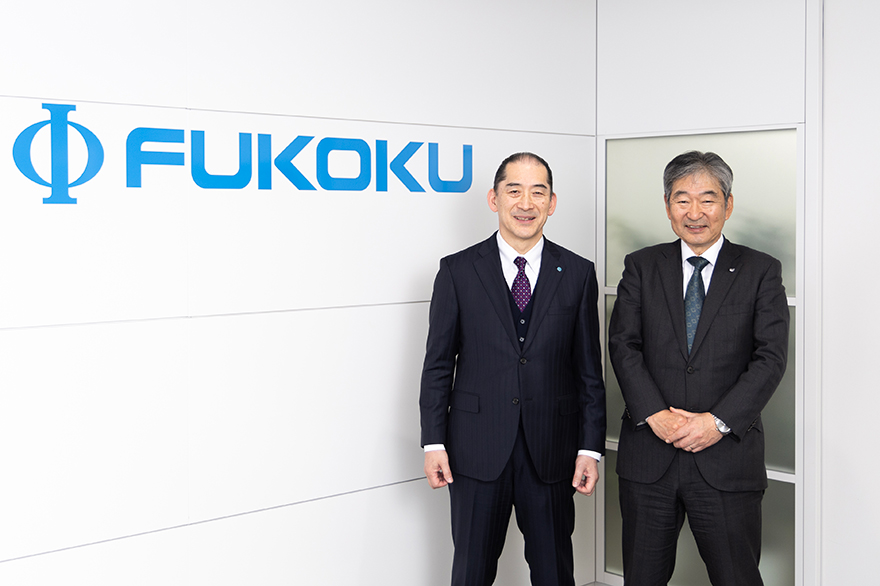 写真:株式会社フコクのロゴの前にて、株式会社フコク代表取締役社長 大城郁男様とキヤノンITソリューションズ株式会社代表取締役社長 金澤 明